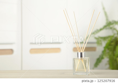 Aroma sticks in glass bottle. Aroma diffuser on table in room 125207916