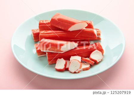 Tasty cut and whole crab sticks on mint table on pink background Tasty cut and whole crab sticks on mint table on pink background 125207919