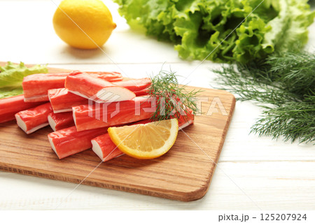 Fresh crab sticks with lemon on cutting board on white background. 125207924