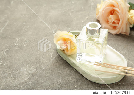 Aromatic reed air freshener and rose on grey concrete background. 125207931