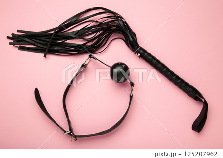 Set of erotic toys for BDSM on pink background. The game of sexual slavery with a whip and gag. Intimate sex games 125207962