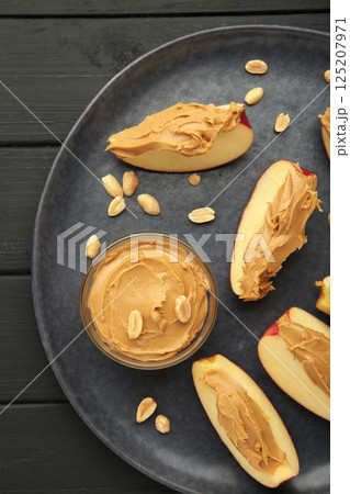 Slices of fresh apple with peanut butter and nuts on dark background. 125207971