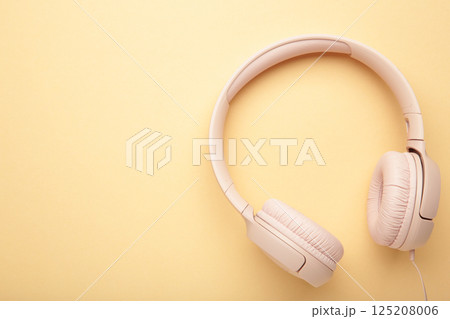 Pink modern headphones on a beige background. Space for text 125208006