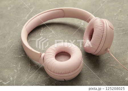Pink modern headphones on grey concrete background Pink modern headphones on grey concrete background 125208025