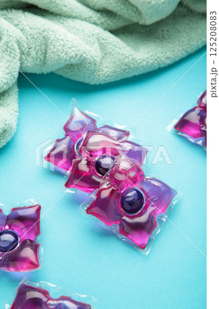 Laundry capsules with mint towel on blue background. Laundry detergent for washing clothes in a washing machine. Vertical photo Laundry capsules with mint towel on blue background. Laundry detergent for washing clothes in a washing machine. Vertical photo 125208083