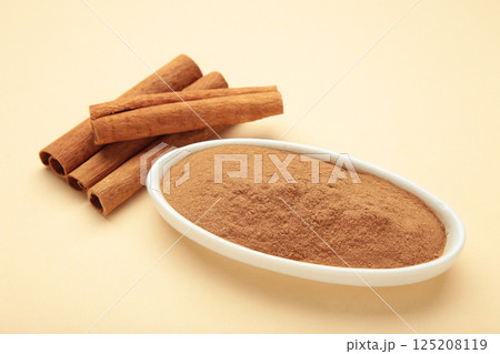 Cinnamon sticks and powder in bowl on beige background. Cinnamon sticks and powder in bowl on beige background. 125208119