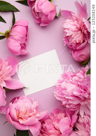 Mockup white greeting card with pink peonies on a purple background. Vertical photo 125208149