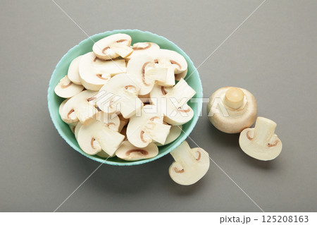 Fresh white champignon mushrooms on mint plate on grey background. 125208163