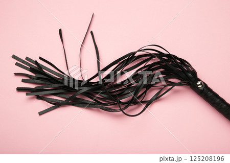 Leather bdsm whip on pink background. Erotic toys for BDSM Leather bdsm whip on pink background. Erotic toys for BDSM 125208196