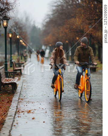 Couple enjoys a leisurely bicycle ride on a rainy day in the park 125209009