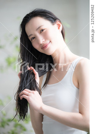 若い女性の濡れた髪にヘアオイルを塗るトリートメントのイメージ 125209482