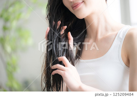 若い女性の濡れた髪にヘアオイルを塗るトリートメントのイメージ 若い女性の濡れた髪にヘアオイルを塗るトリートメントのイメージ 125209484