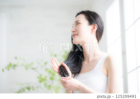 若い女性の濡れた髪のヘアオイルを塗るトリートメント　毛先の枝毛などをケアするイメージ見上げる 125209491