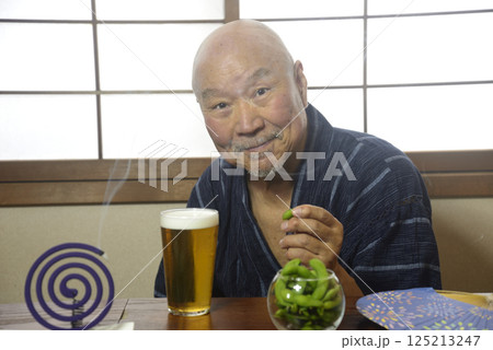 蚊取り線香を焚きビールを楽しむ老人 125213247