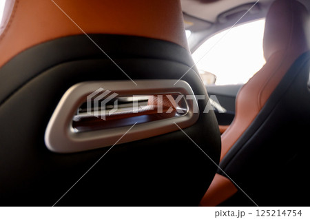 Interior view of a car showcasing brown leather seats with black seat belts. 125214754