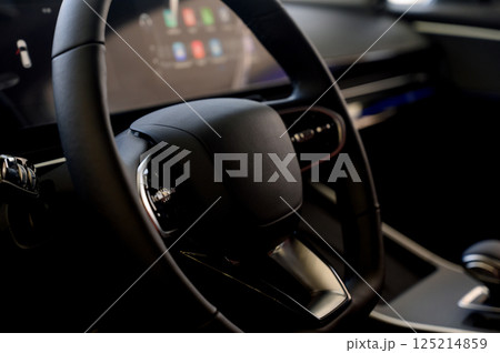 Modern car interior with black steering wheel, digital instrument panel 125214859