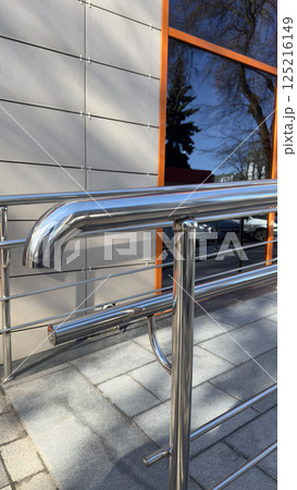 Silver handrails to maintain balance when climbing ramp at entrance of buildings. Vertical photo of handrails and ramp for wheelchair and baby carriage to comfortably enter building Silver handrails to maintain balance when climbing ramp at entrance of buildings. Vertical photo of handrails and ramp for wheelchair and baby carriage to comfortably enter building 125216149