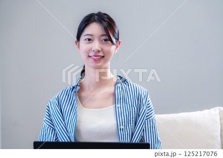 家で笑顔でパソコンを使う若い女性 家で笑顔でパソコンを使う若い女性 125217076