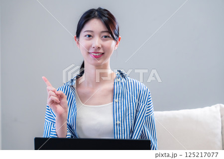 家で笑顔でパソコンを使う若い女性 125217077
