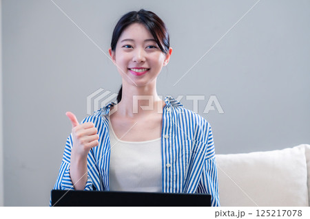 家で笑顔でパソコンを使う若い女性 家で笑顔でパソコンを使う若い女性 125217078