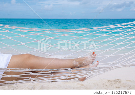 A young woman  is lying in a hammock near the ocean 125217675