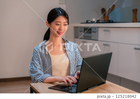 夜遅くまで在宅勤務をする若い女性 125218042