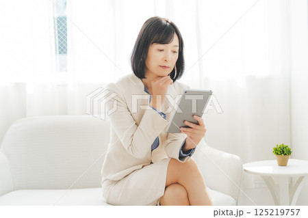 タブレットでデータを見ながら会話するミドルキャリアウーマン 125219757