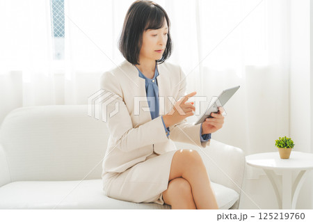 タブレットでデータを見ながら会話するミドルキャリアウーマン 125219760