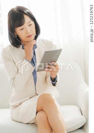 タブレットでデータを見ながら会話するミドルキャリアウーマン 125219763