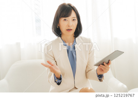 タブレットでデータを見ながら会話するミドルキャリアウーマン 125219767