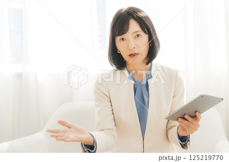 タブレットでデータを見ながら会話するミドルキャリアウーマン 125219770