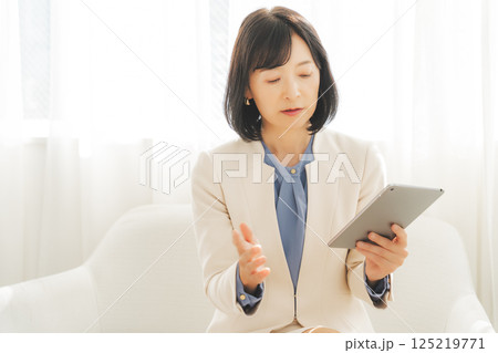 タブレットでデータを見ながら会話するミドルキャリアウーマン 125219771