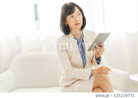 タブレットでデータを見ながら会話するミドルキャリアウーマン 125219772