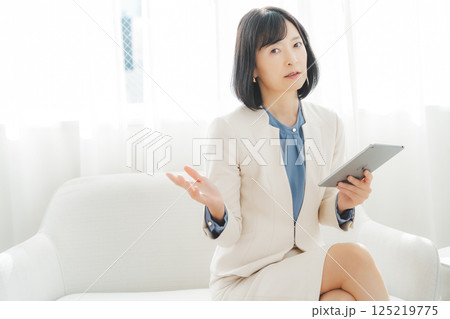 タブレットでデータを見ながら会話するミドルキャリアウーマン 125219775