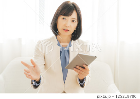 タブレットでデータを見ながら会話するミドルキャリアウーマン 125219780