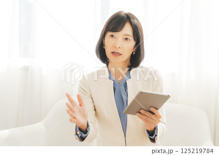 タブレットでデータを見ながら会話するミドルキャリアウーマン 125219784
