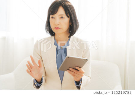 タブレットでデータを見ながら会話するミドルキャリアウーマン タブレットでデータを見ながら会話するミドルキャリアウーマン 125219785