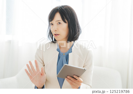 タブレットでデータを見ながら会話するミドルキャリアウーマン 125219786