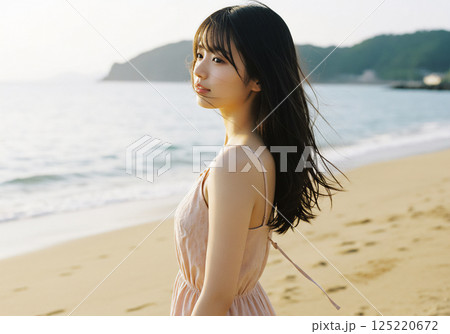風が吹く海岸沿いに佇む女性 125220672