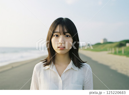 風が吹く海岸沿いに佇む女性 125220683