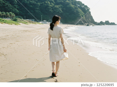 穏やかな夏の砂浜を歩く女性 125220695