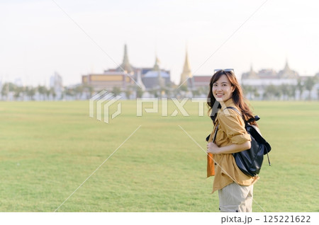 Traveler asian woman in her 30s captures the majesty of the Emerald Buddha. Immerse yourself in the spiritual heart of Bangkok with her. 125221622