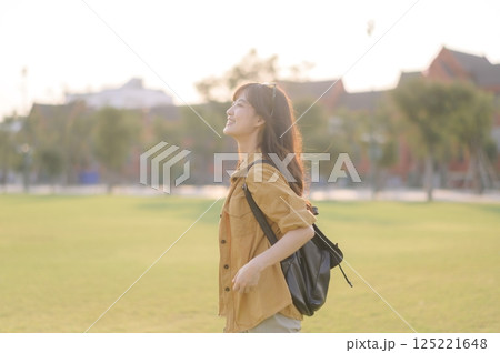 Traveler asian woman in her 30s stands bathed in the golden glow of sunset, embracing the freedom of exploration. on summer holiday weekend vacation trip in Bangkok, Thailand Traveler asian woman in her 30s stands bathed in the golden glow of sunset, embracing the freedom of exploration. on summer holiday weekend vacation trip in Bangkok, Thailand 125221648