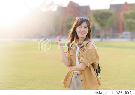 Traveler asian woman in her 30s stands bathed in the golden glow of sunset, embracing the freedom of exploration. on summer holiday weekend vacation trip in Bangkok, Thailand 125221654