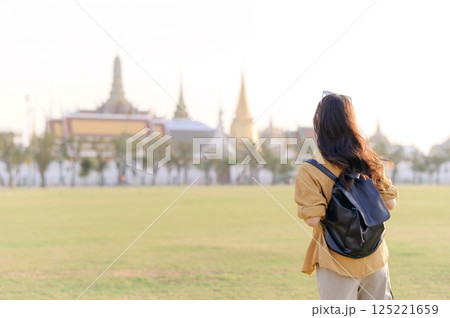 A Traveler Asian woman in her 30s exploring Wat Pra Kaew. From stunning architecture to friendly locals, she cherishes every moment, capturing it all in her heart and camera for years to come. 125221659