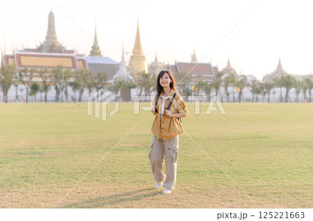 A Traveler Asian woman in her 30s exploring Wat Pra Kaew. From stunning architecture to friendly locals, she cherishes every moment, capturing it all in her heart and camera for years to come. 125221663