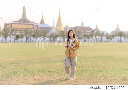 A Traveler Asian woman in her 30s exploring Wat Pra Kaew. From stunning architecture to friendly locals, she cherishes every moment, capturing it all in her heart and camera for years to come. A Traveler Asian woman in her 30s exploring Wat Pra Kaew. From stunning architecture to friendly locals, she cherishes every moment, capturing it all in her heart and camera for years to come. 125221665
