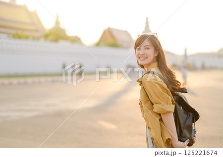 Traveler asian woman in her 30s stands bathed in the golden glow of sunset, embracing the freedom of exploration. on summer holiday weekend vacation trip in Bangkok, Thailand Traveler asian woman in her 30s stands bathed in the golden glow of sunset, embracing the freedom of exploration. on summer holiday weekend vacation trip in Bangkok, Thailand 125221674