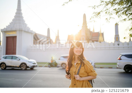 Traveler asian woman in her 30s stands bathed in the golden glow of sunset, embracing the freedom of exploration. on summer holiday weekend vacation trip in Bangkok, Thailand Traveler asian woman in her 30s stands bathed in the golden glow of sunset, embracing the freedom of exploration. on summer holiday weekend vacation trip in Bangkok, Thailand 125221679