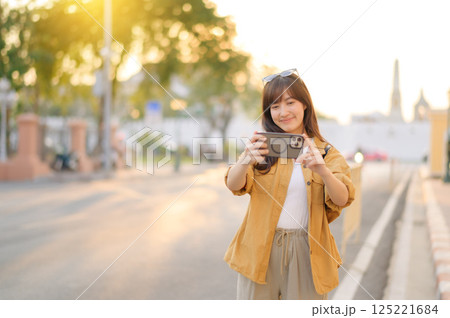 Traveler asian woman in her 30s using smartphone to take a photo while traveling urban street in Bangkok, Thailand Traveler asian woman in her 30s using smartphone to take a photo while traveling urban street in Bangkok, Thailand 125221684